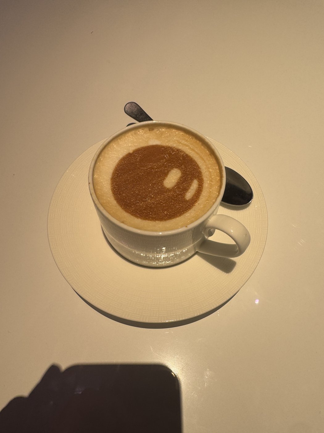 A cup of coffee with a Grok Bot face in the foam at Cursor Compile London